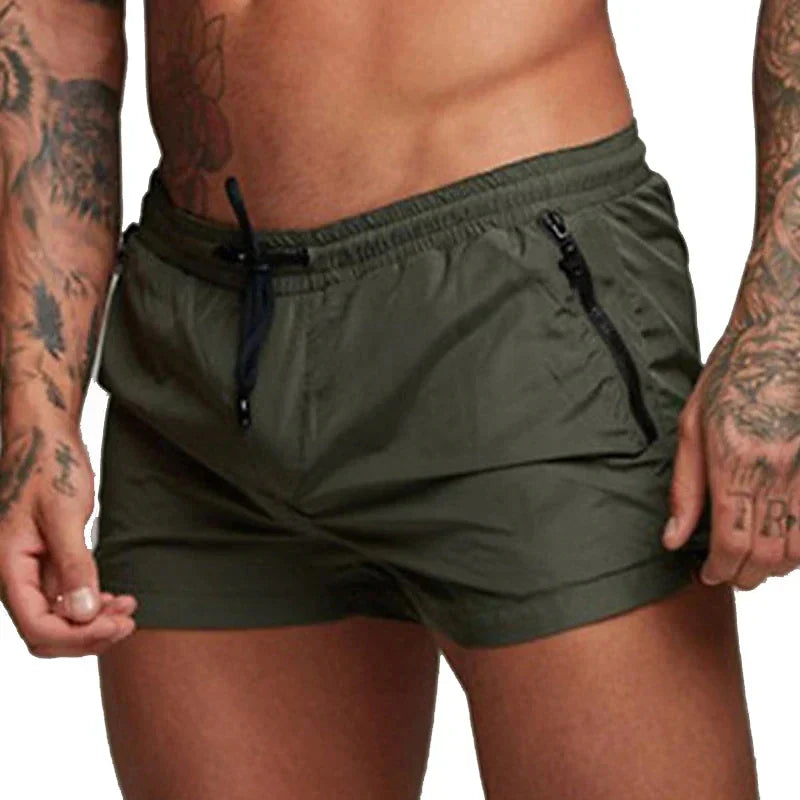 Short de bain vert homme porté de face, taille à cordon et poches zippées