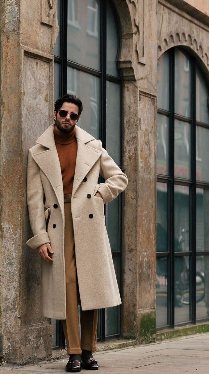 Homme en manteau beige devant une façade urbaine